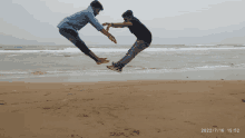 two men jumping in the air on a beach with the date 2022/7/16