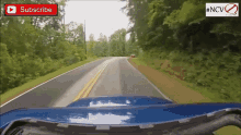 a blue car is driving down a road with a youtube subscribe button