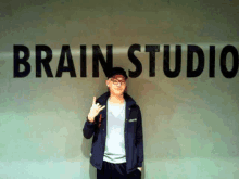 a man is standing in front of a wall that says brain studio