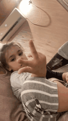 a little girl is laying on the floor with her hand up in front of a wall air conditioner