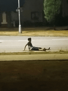 a man is laying on the side of the road at night