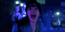 a woman is screaming with her mouth wide open in a dark room