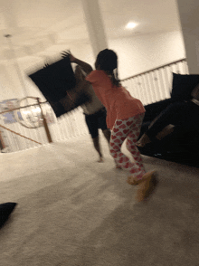 a man and a little girl are having a pillow fight in a living room