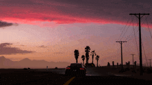 a car driving down a road with palm trees in the background