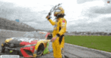 a man in a yellow suit is standing in front of a race car