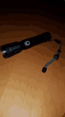 a flashlight is sitting on a wooden table with a strap .