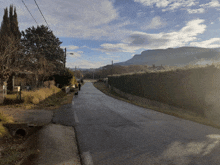 a person walking a dog down a road with a mountain in the background