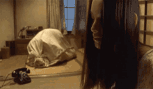 a woman with long hair is standing in a room with a telephone on the floor .