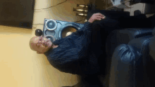 a man in a striped shirt is sitting in front of a speaker