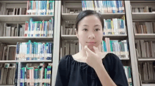 a woman stands in front of a bookshelf with a book titled ' a brief history of the world '