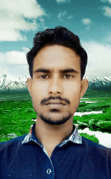 a man in a blue shirt stands in front of a mountain