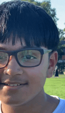 a young boy wearing glasses and a white shirt smiles for the camera