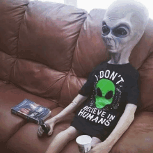 an alien is sitting on a couch wearing a shirt that says " do n't believe in humans " on it