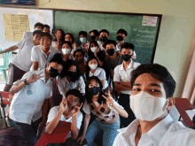 a group of students wearing face masks pose for a picture in front of a blackboard that says ' a ' on it