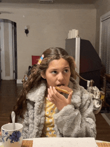 a girl in a fur coat eating a donut