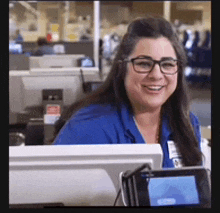 a woman wearing glasses and a blue shirt is smiling at the camera