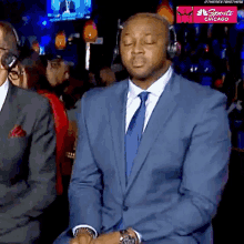 a man in a suit and tie is sitting with his eyes closed in front of a sign that says sports chicago