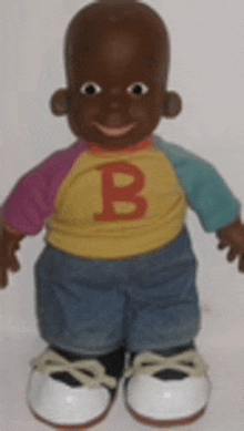 a black doll with a yellow shirt with the letter b on it