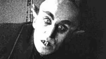 a black and white photo of a vampire with huge teeth and ears .