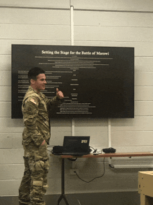 a man in a military uniform stands in front of a large screen that says setting the stage for the battle of marawi