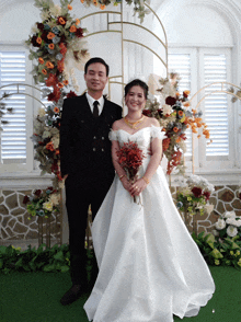 a bride and groom are posing for a picture in front of flowers