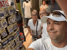 a man wearing a white shirt with the word full on it stands in front of a display of souvenirs