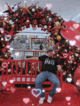 a man is sitting on a bench in front of a christmas tree and a sign that says sm city