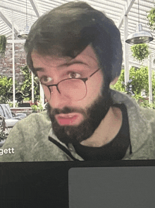 a man with glasses and a beard has the word gett on the bottom of the screen