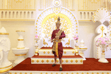 a man in a red and gold outfit stands in front of a throne