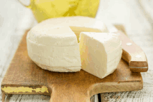 a sliced piece of cheese sits on a wooden cutting board next to a knife