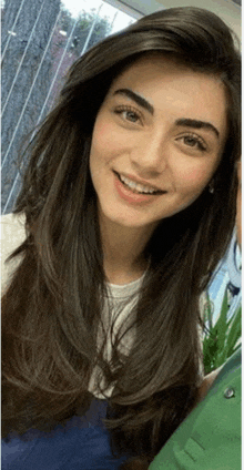 a woman with long hair is smiling for the camera while wearing a white shirt .