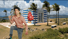 a man is holding a bag with the letter b on it in front of a striped building