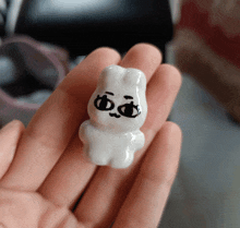 a person is holding a small white figurine with a face painted on it