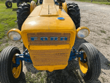 a yellow ford tractor is parked on the side of a dirt road