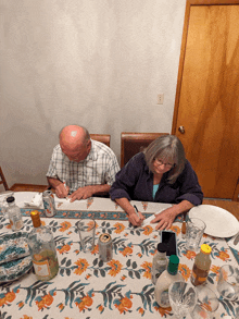 a man and a woman sit at a table with a bottle of orange juice on it