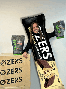 a woman holds up a zer 's protein bar next to a bag of post workout