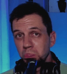 a man wearing headphones is making a funny face while holding a microphone in his mouth .