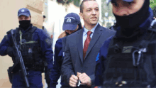 a man in a suit is surrounded by a group of police officers