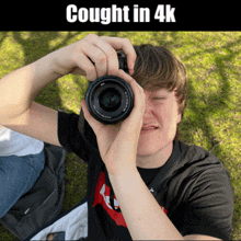 a young man is taking a picture with a camera with the words caught in 4k below him