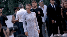 a woman in a white lace dress is standing in front of a crowd of people and says gettyimages on the bottom