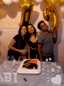 three people are posing for a picture in front of a table with a cake and balloons and the word abi on it