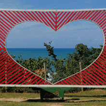 a red and white heart shaped fence with a green bench in front of it