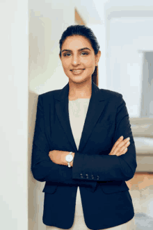 a woman in a suit is standing with her arms crossed and wearing a watch