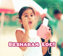 a little girl is holding a pink camera and says " besharam log "