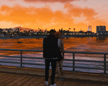 a man and a woman standing on a pier looking at the water