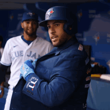 a man in a blue jays uniform is standing in the dugout