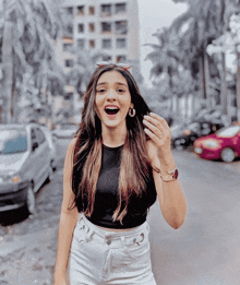 a woman wearing a black crop top and white shorts is smiling for the camera