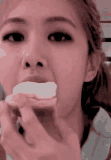 a close up of a woman 's face eating a piece of food .