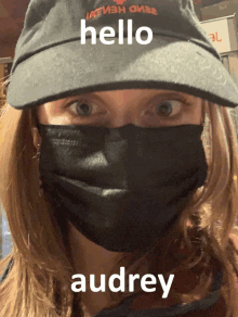 a woman wearing a mask and a hat with the words hello audrey on it