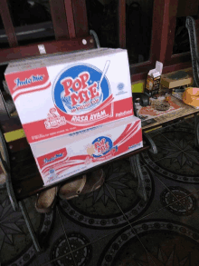 two boxes of pop mie sit on a bench